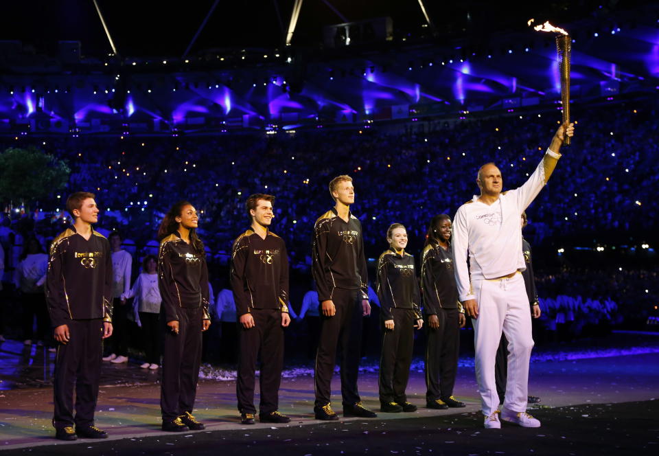 Steve Redgrave, right, holds the Olympic torch after entering the stadium during the Opening Ceremony at the 2012 Summer Olympics, Saturday, July 28, 2012, in London. (AP Photo/Matt Dunham, Pool)