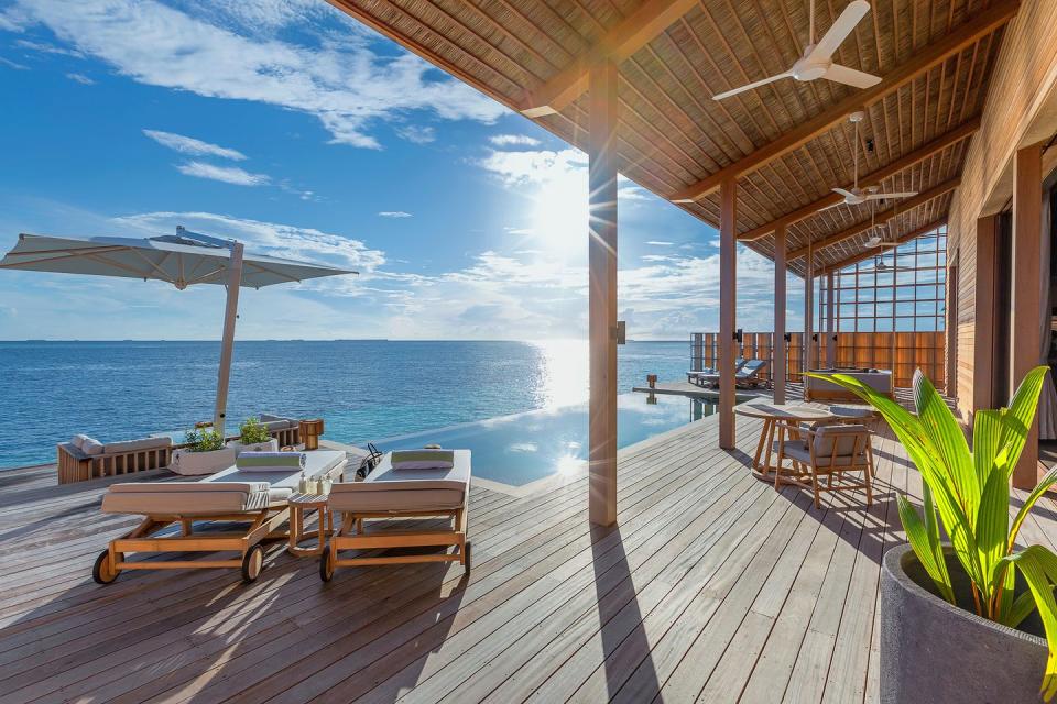 a deck with tables and chairs on it next to a body of water