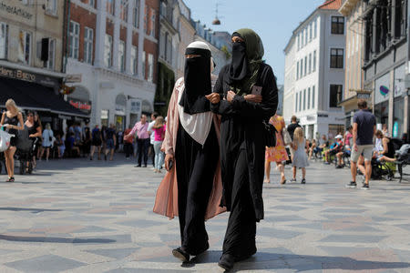 Anna-Bella (L), 26, a home care worker and Amina, 24, a student, both members of the group Kvinder I Dialog (Women In Dialogue) and wearers of the niqab, walk along Stroget, the main shopping strip in Copenhagen, Denmark, July 26, 2018. REUTERS/Andrew Kelly
