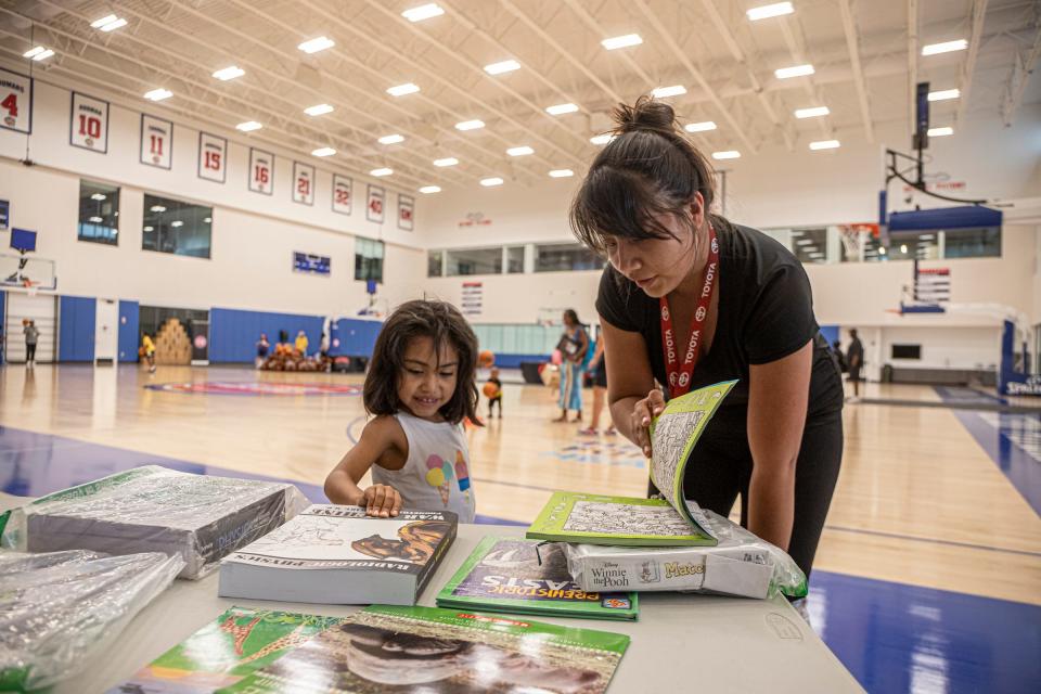 Dayana Fuentes, 4, picks out books with her mother, Rosario Rojas, 27, both of Detroit, during the Pistons' back to school drive at the Detroit Pistons Performance center in New Center, Detroit, on Monday, Aug. 15, 2022.