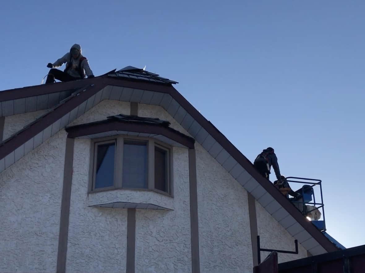 Employees of Goodmen Roofing install a new roof on a house in Red Deer, Alta. The company offers $500 to any employee who brings in another worker and to workers who stay at least six months.  (Bryan Labby/CBC - image credit)