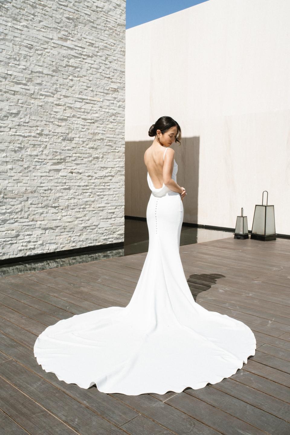 A bride looks over her shoulder at her backless wedding dress.