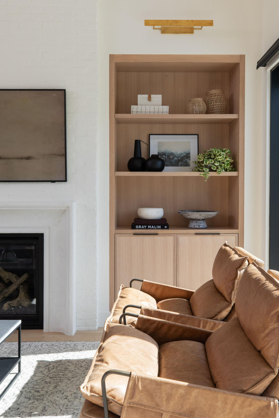 A set of shelves in a living room alcove decorated with books, a bowl, a plant, and other decor