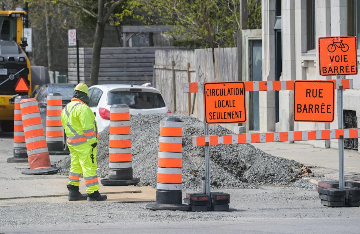 A worker is shown next to construction cones in Montreal, Tuesday, April 25, 2023. The cones are going to be out in force in the fall.  (Graham Hughes/The Canadian Press - image credit)