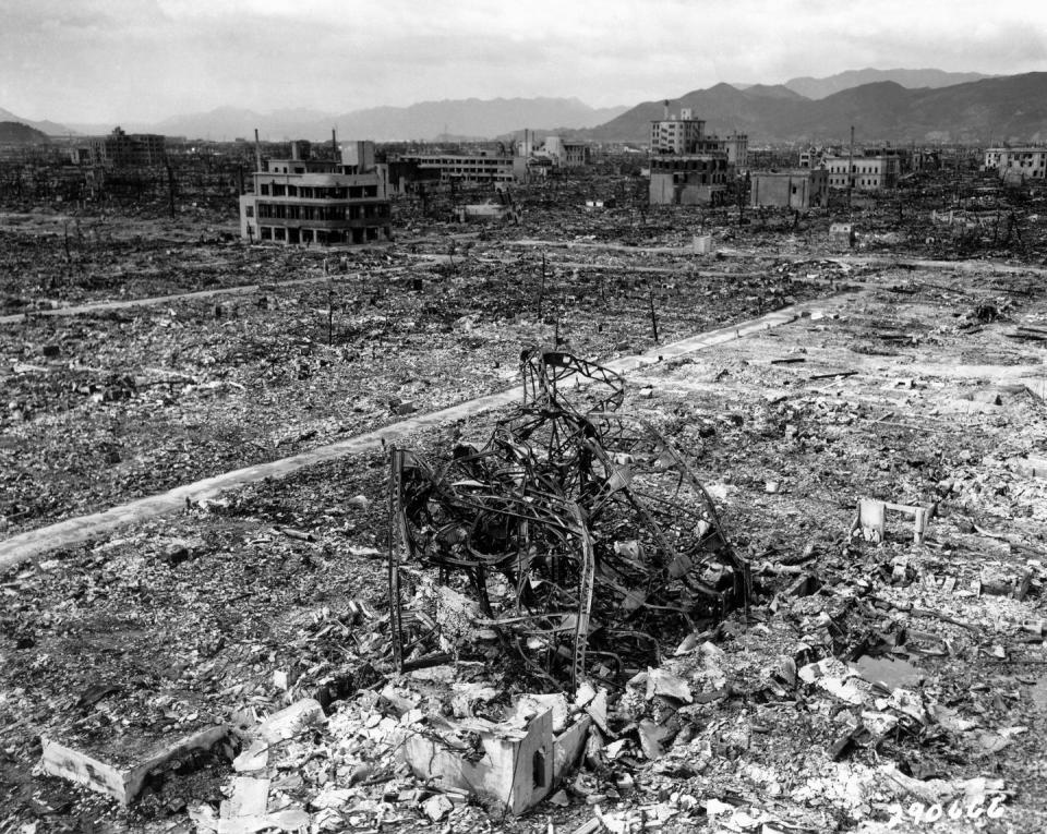 rubble and ruins in the foreground, some still standing buildings and mountains appear in the background