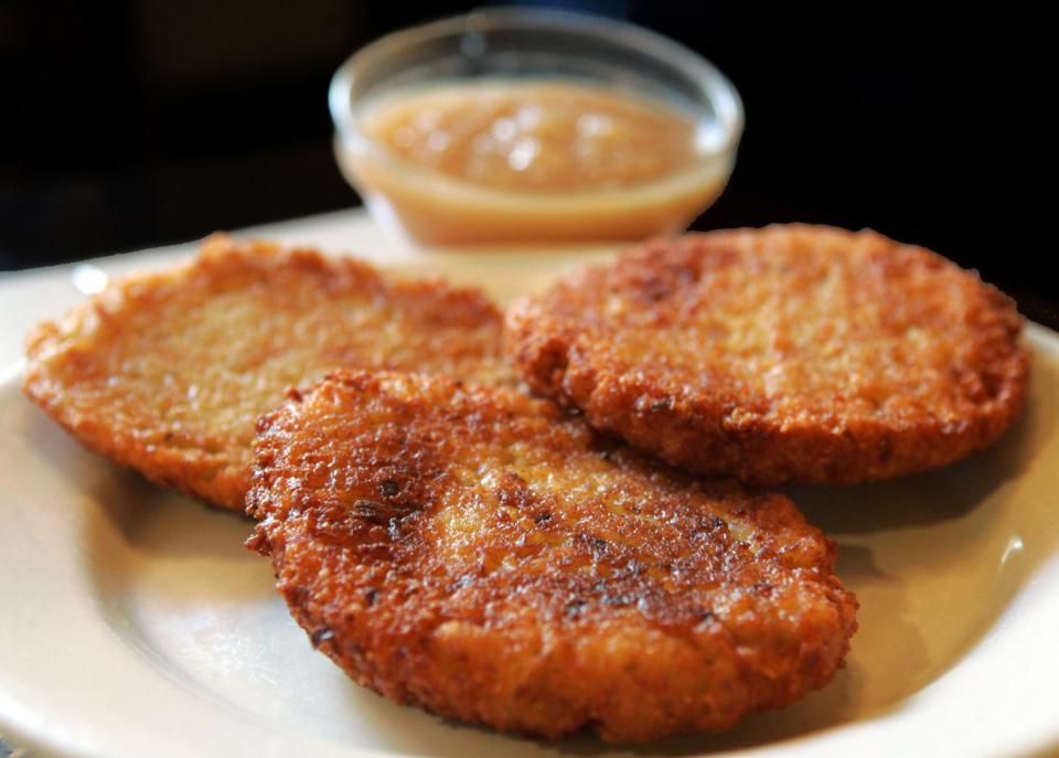 A serving of golden-fried potato latkes served with apple sauce. Latkes have one of the most honored places in Hanukkah's culinary tradition. Today, many different varieties of latkes celebrate the wealth of ingredients beyond potatoes at our disposal - a latke party with two or more kinds of latkes can surely add to the festivities. (AP Photo/Mary Altaffer)