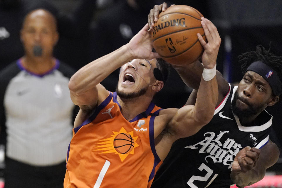 Phoenix Suns guard Devin Booker, left, is folded by Los Angeles Clippers guard Patrick Beverley as he tries to shoot during the first half in Game 3 of the NBA basketball Western Conference Finals Thursday, June 24, 2021, in Los Angeles. (AP Photo/Mark J. Terrill)