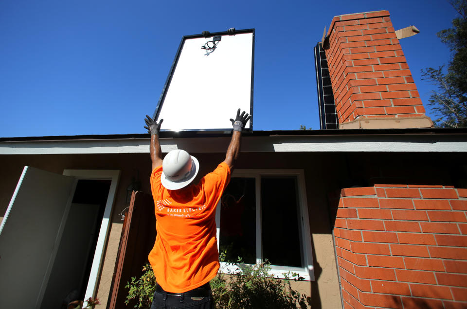 Workers lift a solar panel onto a roof during a residential solar installation in Scripps Ranch, San Diego, California, U.S. October 14, 2016. Picture taken October 14, 2016.      REUTERS/Mike Blake