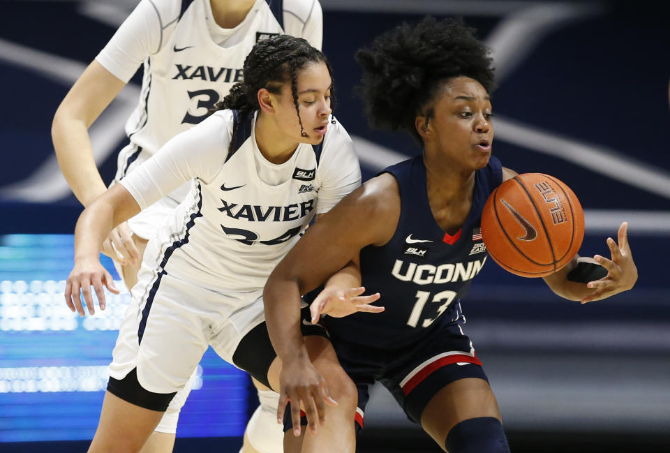 Connecticut guard Christyn Williams, right, takes control of a loose ball in front of Xavier guard Shaulana Wagner (24) during the first half of an NCAA college basketball game Saturday, Feb. 20, 2021, in Cincinnati. (AP Photo/Gary Landers)