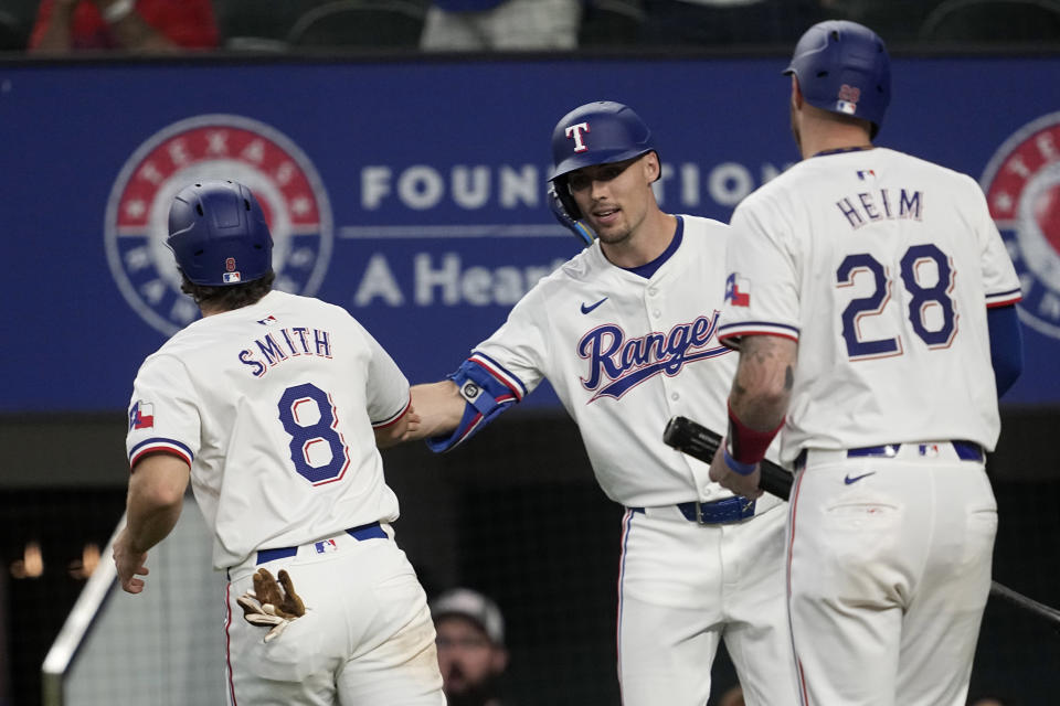 Texas Rangers' Josh Smith (8) and Jonah Heim (28) celebrate with Evan Carter, center, after scoring on an Travis Jankowski single in the eighth inning of a baseball game against the Washington Nationals in Arlington, Texas, Thursday, May 2, 2024. (AP Photo/Tony Gutierrez)
