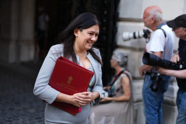 A woman in a pale blue suit carries a red file