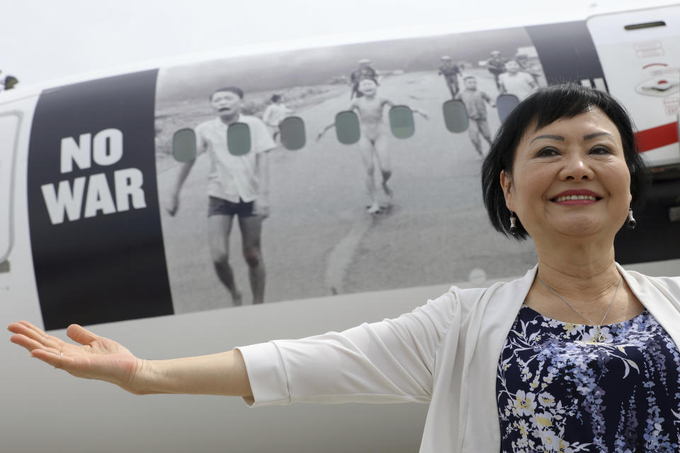 Kim Phuc, la niña de la famosa foto del ataque con napalm en Vietnam que fue captada en 1972, posa para una foto delante de un avión que transporta a refugiados que huyen de la guerra en Ucrania a Canadá, el lunes 4 de julio de 2022, en el aeropuerto Frederic Chopin de Varsovia, Polonia. (AP Foto/Michal Dyjuk)