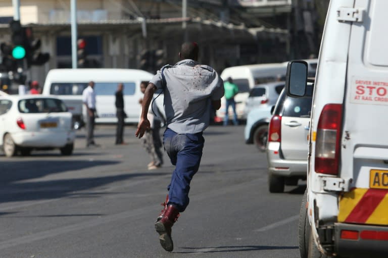 An injured Zimbabwean policeman runs away after clashing with supporters of opposition party Movement for Democratic Change Tsvangirai faction (MDC-T) during a march against police brutality in Harare on August 24, 2016