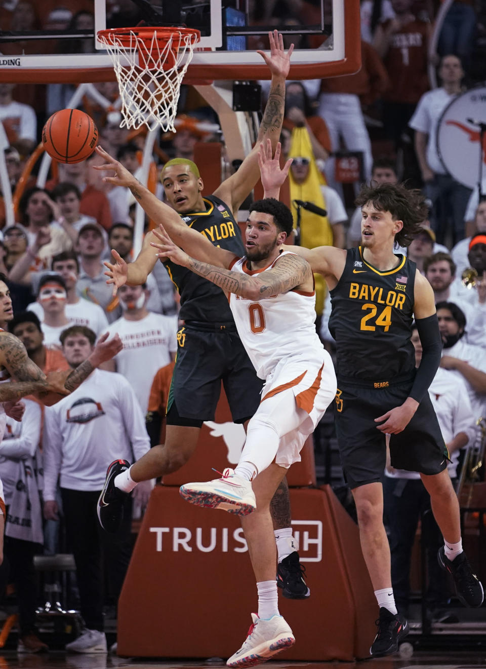 Texas forward Timmy Allen (0) reaches for a rebound against Baylor forward Jeremy Sochan, left, and guard Matthew Mayer (24) during the first half of an NCAA college basketball game Monday, Feb. 28, 2022, in Austin, Texas. (AP Photo/Eric Gay)