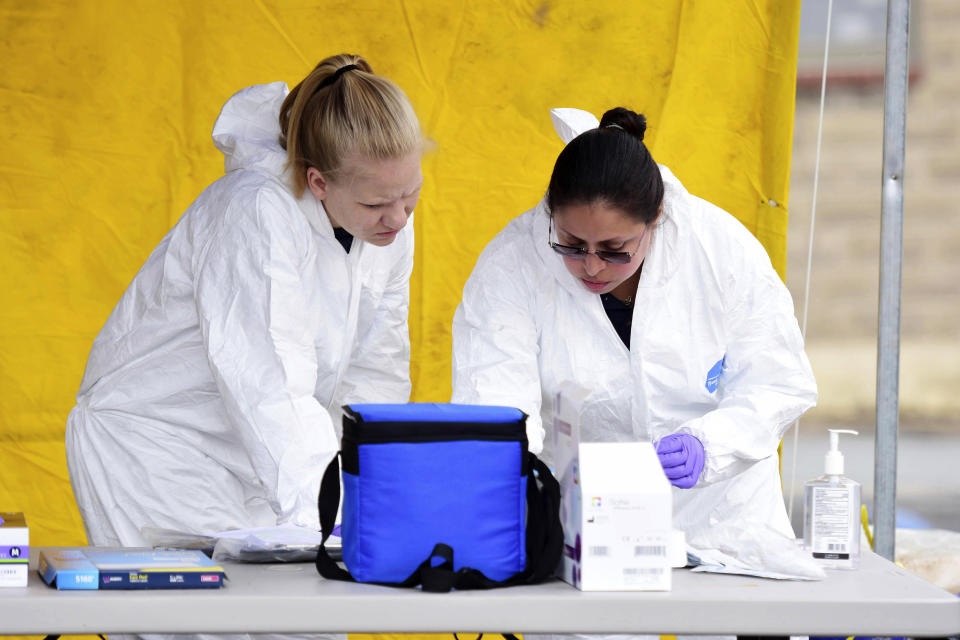 Moriyah Cox, left, and Raisa Wheeler, both with Mt. Hope EMS, work on flu and coronavirus tests during drive-thru testing by the Fayette County Health Department in Oak Hill, W.V. on Thursday, March 19, 2020. (Chris Jackson/The Register-Herald via AP)