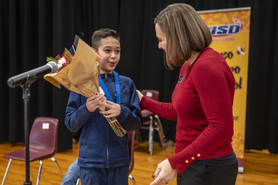 Jennifer Harrell, the Pflugerville school district’s dual-language coordinator, hands Luis Orlando Ruiz Medina flowers after he won the Pflugerville district's Spanish Language Spelling bee on Saturday.