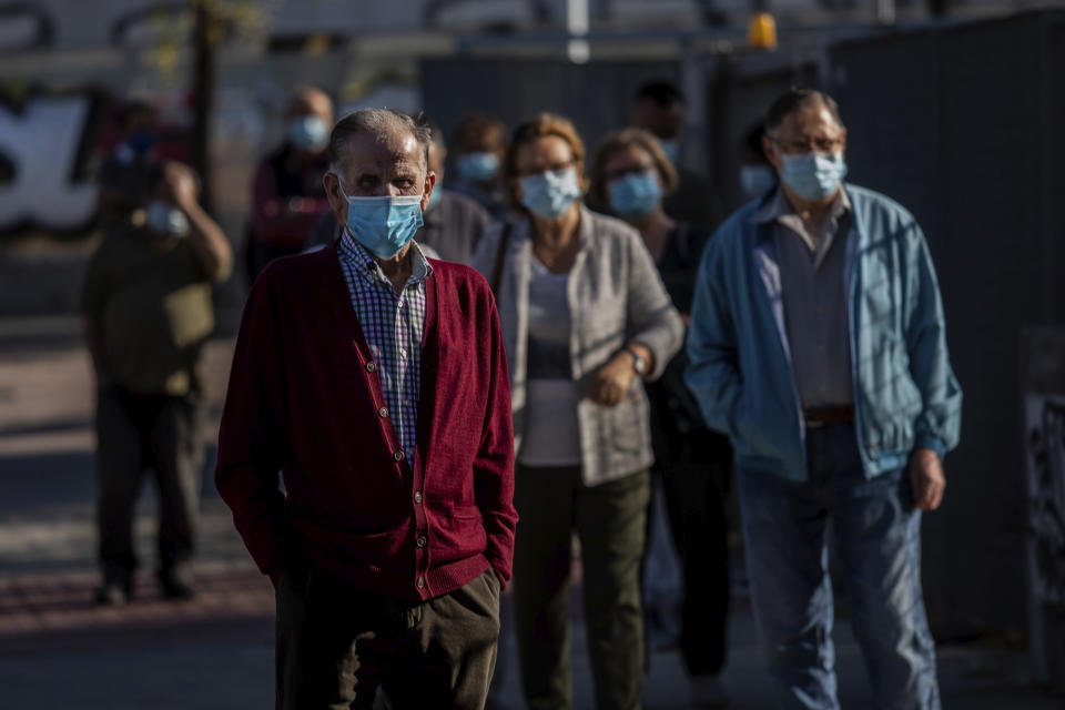 People queue for a rapid antigen test for COVID-19 in the southern neighbourhood of Vallecas in Madrid, Spain, Thursday, Oct. 1, 2020. Madrid and its suburbs are preparing to enter a soft lockdown that restricts trips and out of the Spanish capital following a weeks-long political turf fight over Europe's latest infection hot spot. (AP Photo/Bernat Armangue)