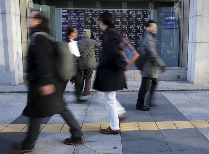 A man (3rd L) looks at an electronic stock quotation board as passers-by walk past, outside a brokerage in Tokyo, Japan January 20, 2016. REUTERS/Toru Hanai/Files