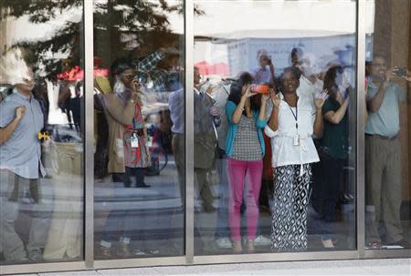 People watch U.S. President Barack Obama and Vice President Joe Biden (both not pictured) walk down the sidewalk after buying lunch at a sandwich shop near the White House in Washington, October 4, 2013. REUTERS/Jonathan Ernst