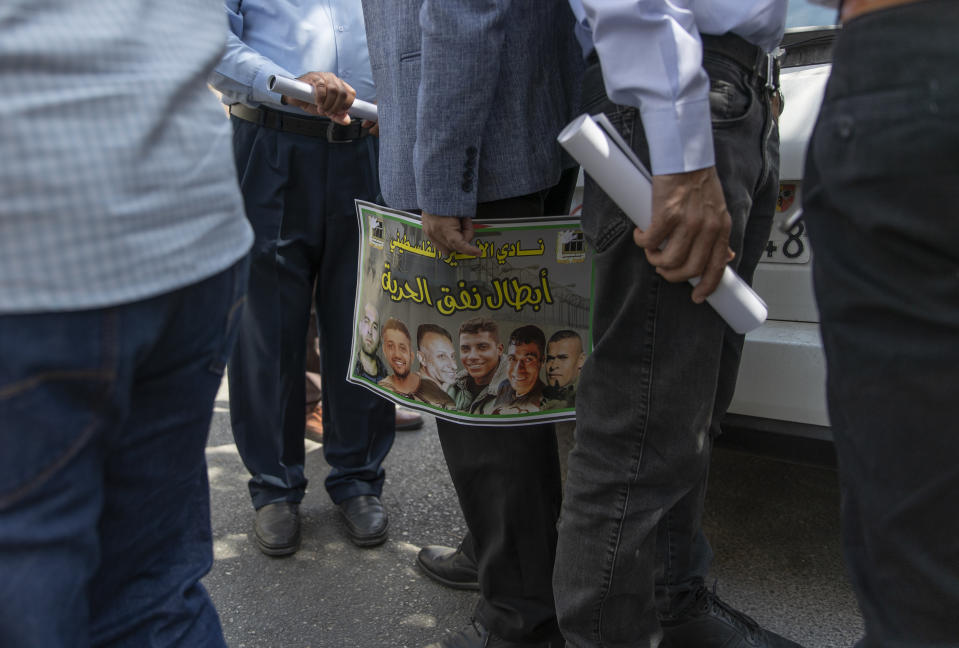 A Palestinian man carries a poster with pictures of the six Palestinian prisoners who escaped from an Israeli jail that says "heroes of the freedom tunnel," during a protest supporting prisoners, in the West Bank city of Ramallah, Tuesday, Sept. 14, 2021. The cinematic escape of six prisoners who tunneled out of an Israeli penitentiary shone a light on Israel's mass incarceration of Palestinians, one of the many bitter fruits of the conflict. (AP Photo/Nasser Nasser)