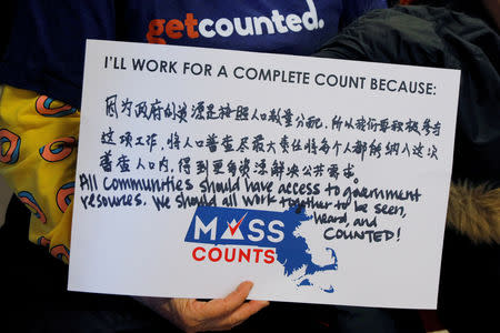 FILE PHOTO: A community activist holds a sign in Chinese and English at an event to mark the one-year-out launch of the 2020 Census efforts in Boston, Massachusetts, U.S., April 1, 2019. REUTERS/Brian Snyder/File Photo