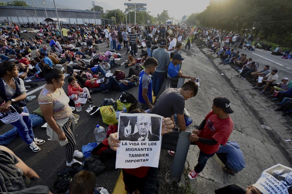 A migrant holds a photo of Mexican President Andrés Manuel López Obrador that reads in Spanish: "The lives of migrants also matter" as their caravan stops to block the highway in Huixtla, Mexico, Wednesday, Nov. 8, 2023. About 3,000 migrants, mostly from Central America, are protesting for the government to issue them temporary documents allowing them to continue north to the U.S. border. (AP Photo/Edgar Clemente)