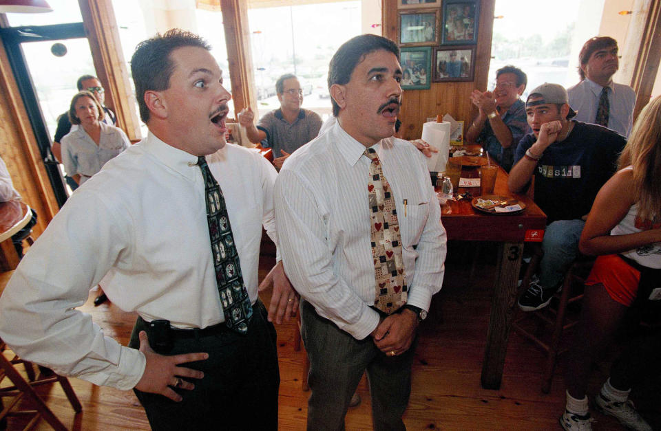 FILE - In this Oct. 3, 1995 file photo, Justin Barker, left, and his colleague Juan Borrego react as they hear the verdict of the O.J. Simpson trial in Miami. For many people old enough to remember O.J. Simpson's murder trial, his 1994 exoneration was a defining moment in their understanding of race, policing and justice. Nearly three decades later, it still reflects the different realities of white and Black Americans. (AP Photo/Marta Lavandier)