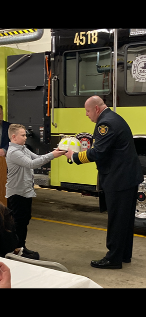 Derek Shaffer, Uniontown's new fire chief, receives the chief's helmet from his son, Colton, during his swearing-in ceremony.