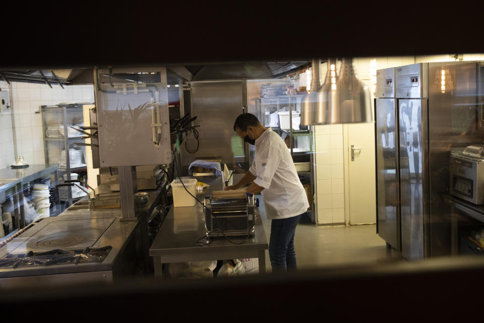 Chef Kayes Ghourabi works in the kitchen as he prepares take-away meals in his restaurant, Tartufo, in Sint-Pieters-Leeuw, Belgium, Thursday, Oct. 22, 2020. The coronavirus pandemic is gathering strength again in Europe and, with winter coming, its restaurant industry is struggling. The spring lockdowns were already devastating for many, and now a new set restrictions is dealing a second blow. Some governments have ordered restaurants closed; others have imposed restrictions curtailing how they operate. (AP Photo/Francisco Seco)