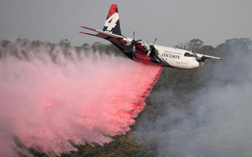 The NSW Rural Fire Service Large Air Tanker (LAT) drops fire retardant on the Morton Fire burning in bushland close to homes at Penrose in the NSW Southern Highlands - REX