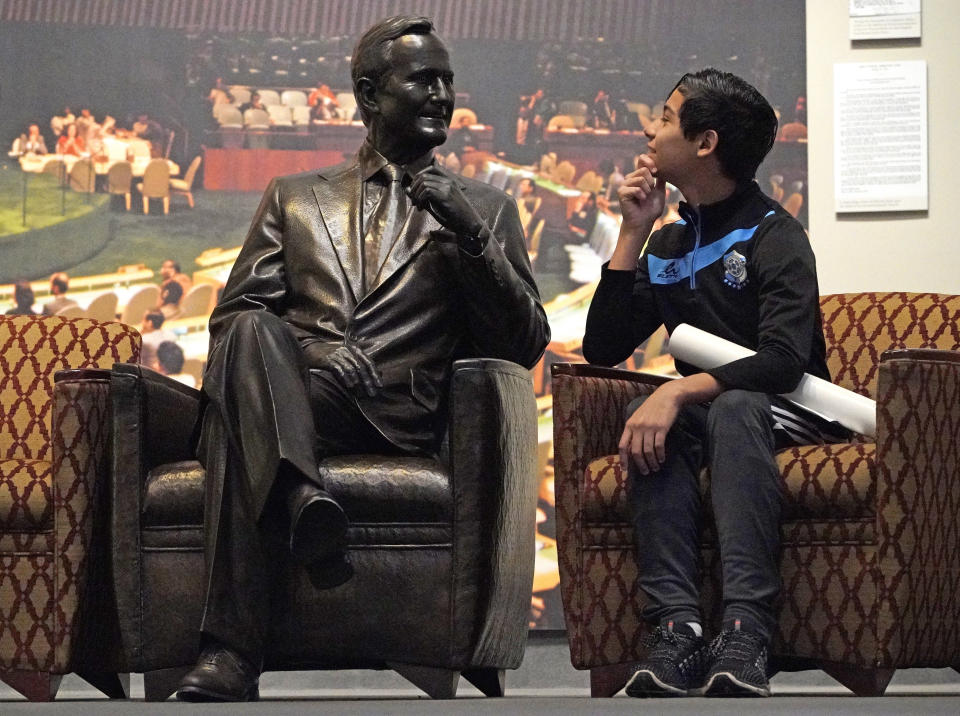 Andrew Lopez, 12, of Midland, Texas, sits next to a statue of George H.W. Bush inside the George H.W. Bush Presidential Library and Museum on Dec. 1, in College Station, Texas. (Photo: David J. Phillip/AP)