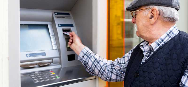 Elderly man uses an ATM.