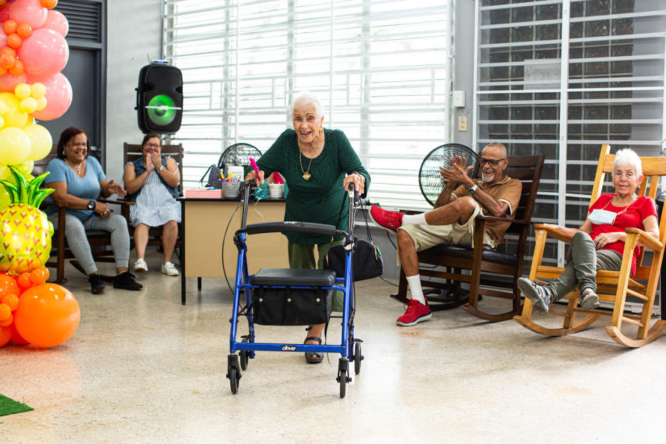 Julia Canals Solis, 96, dances a bolero with her walker as others cheer her on at the Center for Activities and Multiple Uses for the Elderly of Toa Baja in Toa Baja, Puerto Rico, on May 26, 2023. (Erika P. Rodríguez for NBC News)