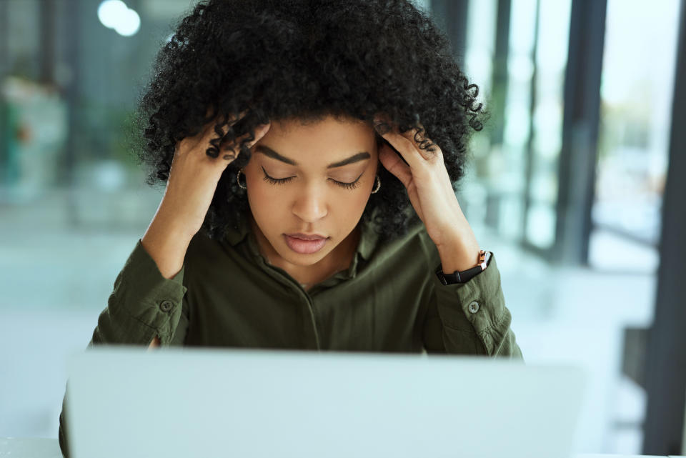 A woman looking stressed in front of her laptop