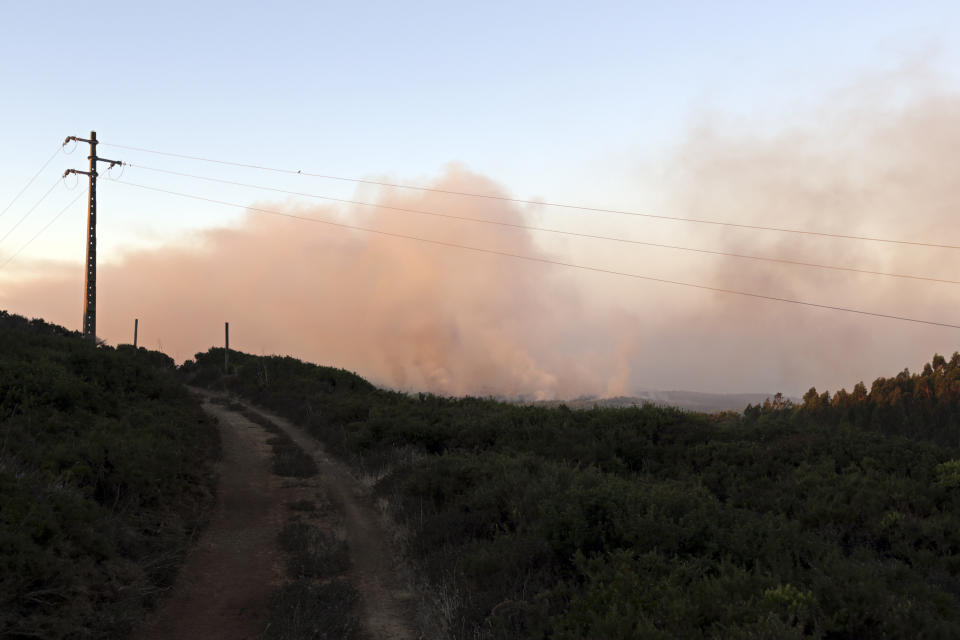 Clouds of smoke from a forest fire are lit by the rising sun near the village of Malveira da Serra, in the Sintra national park, west of Lisbon, Sunday, Oct. 7, 2018. Over 700 firefighters were battling a forest fire that started overnight about 40 kilometers (25 miles) west of Lisbon. (AP Photo/Armando Franca)