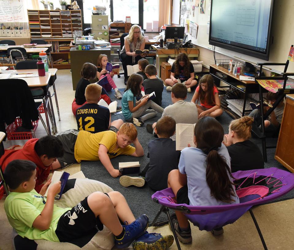 Mason Central fourth grade teacher Jill Bennett reads the book "Holes" by Louis Sachar as her students follow.