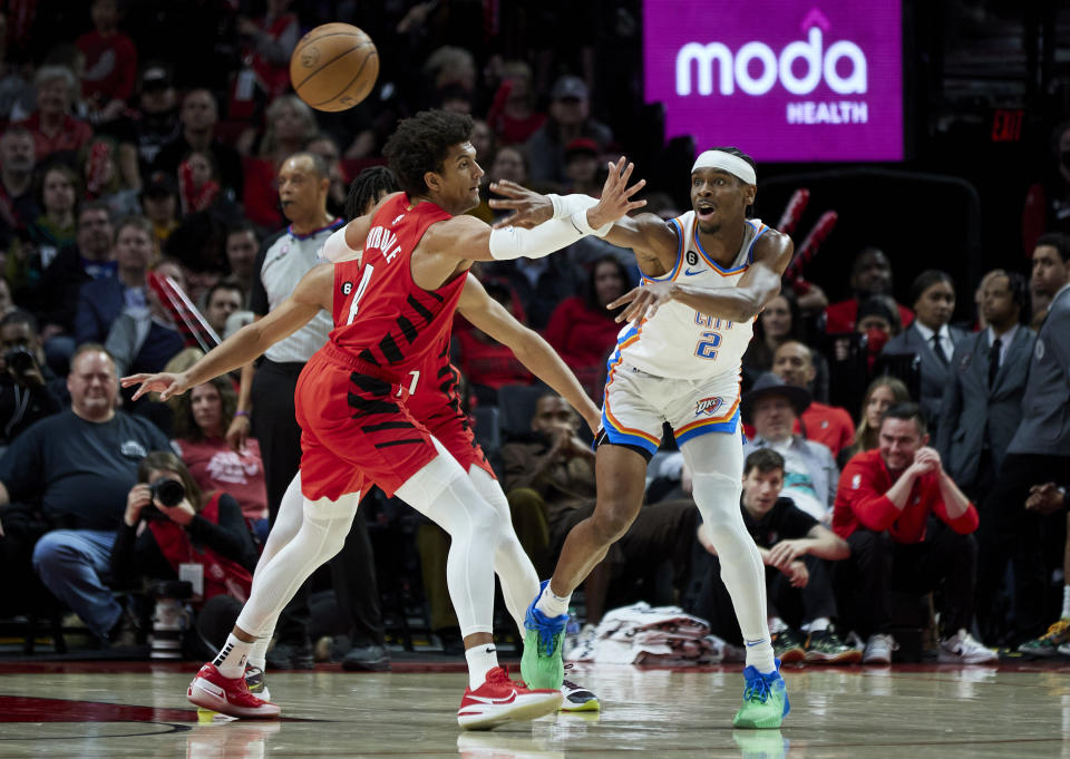 Oklahoma City Thunder guard Shai Gilgeous-Alexander, right, passes the ball away from Portland Trail Blazers guard Matisse Thybulle during the second half of an NBA basketball game in Portland, Ore., Sunday, March 26, 2023. (AP Photo/Craig Mitchelldyer)