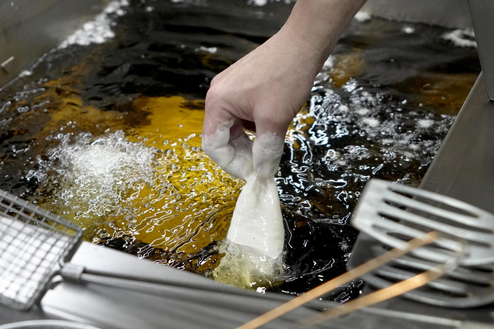 A piece of battered fish is dropped into hot sunflower oil to make traditional fish and chips, at Olleys Fish Experience in Herne Hill in London, Thursday, April 21, 2022.  / Credit: Kirsty Wigglesworth / AP