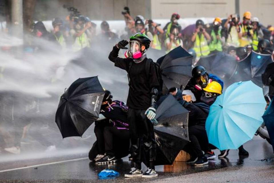 Pro-democracy protesters react as police fire water cannons outside the government headquarters in Hong Kong in 2019 (AFP/Getty)
