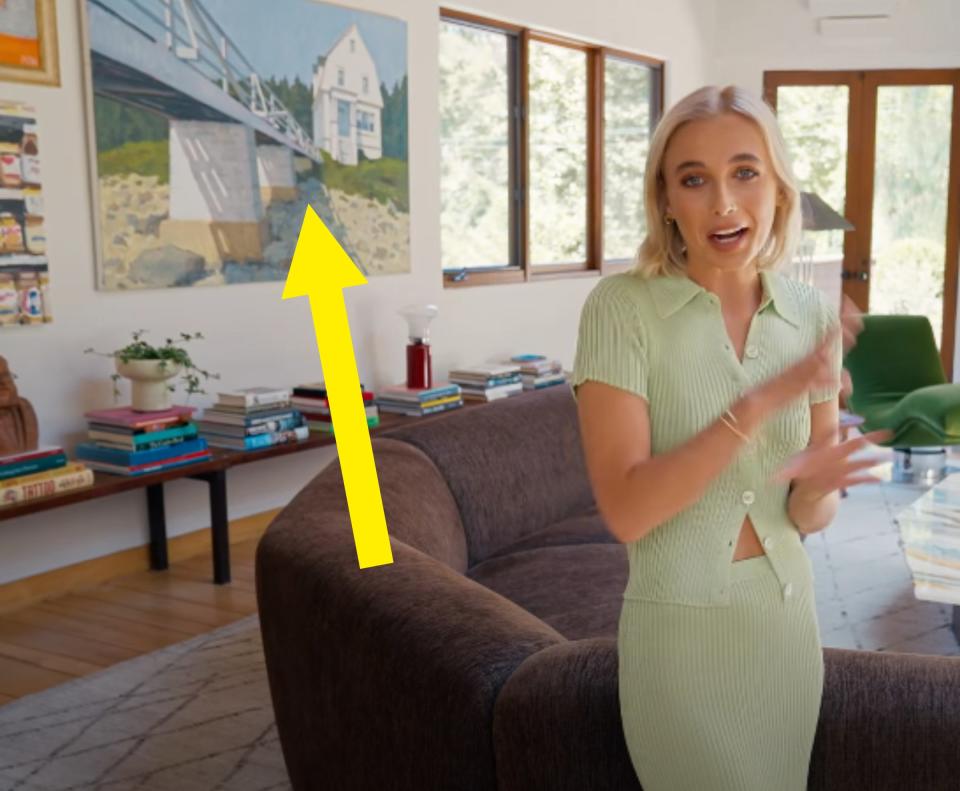 Emma in her home with an arrow pointing to one of her dad's paintings