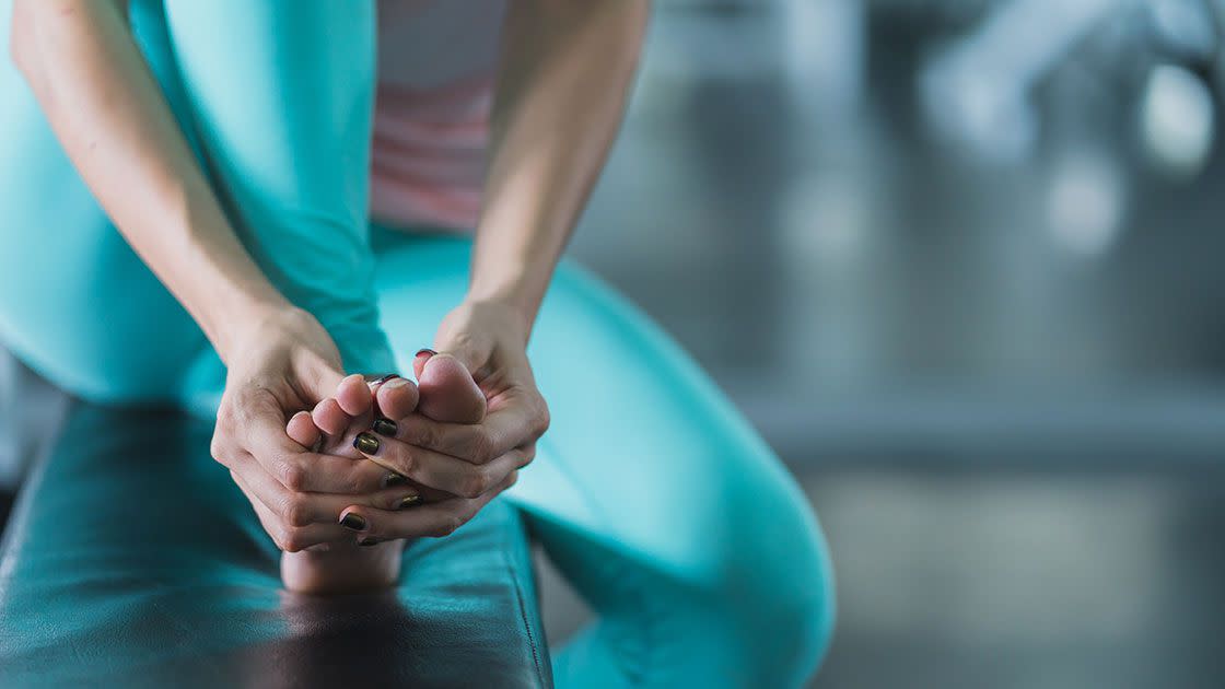 athlete holding injured foot in gym