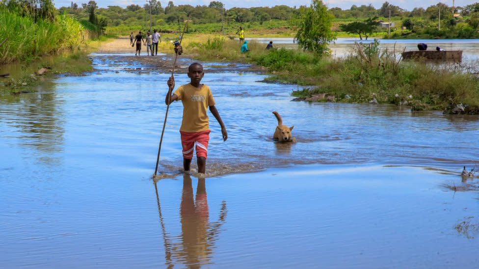 A young boy and his dog cross the flooded Athi River in Joska, Kenya - 23 April 2024 i