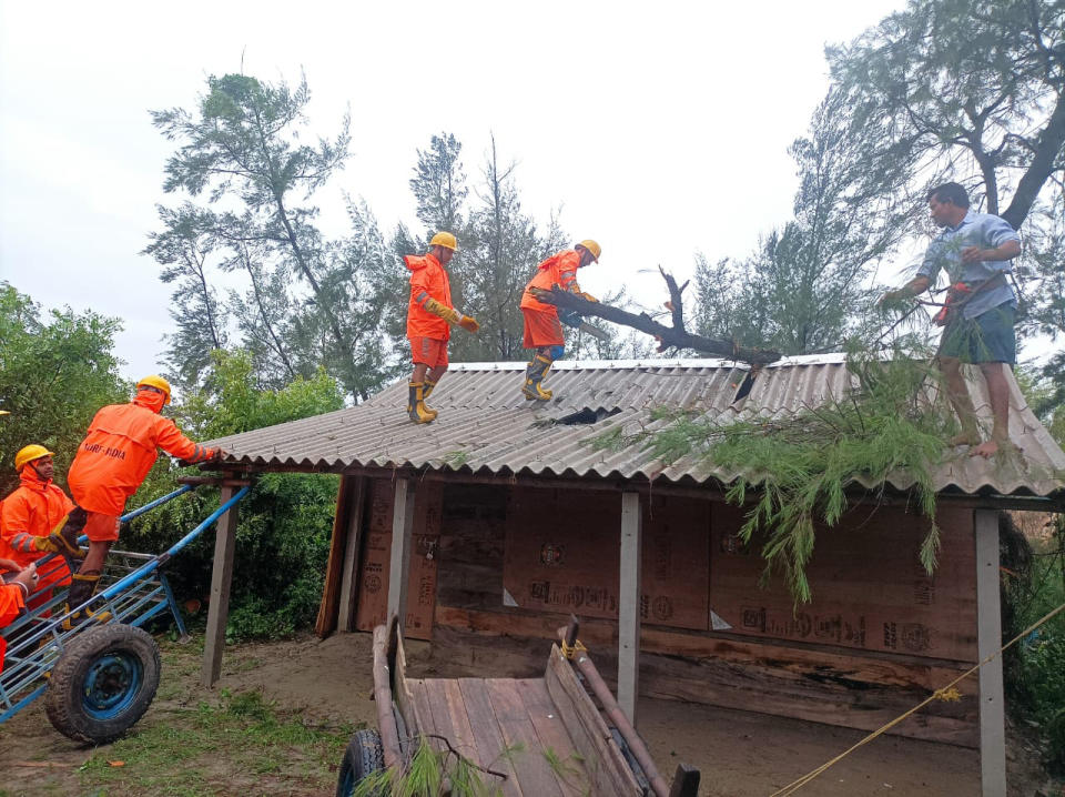 India's National Disaster Response Force (NDRF) rescuers remove fallen tree branches on the roof of a house as they oversee damages in Cyclone Remal affected villages in West Bengal state, India, Monday, May 27, 2024. (NDRF via AP)