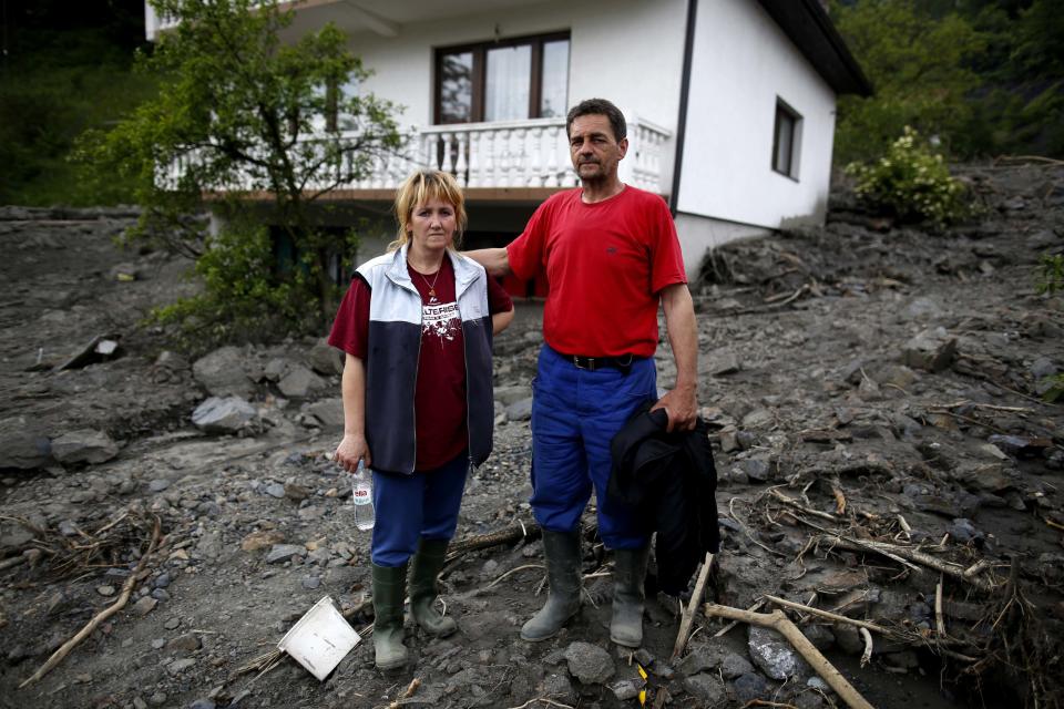 Zehid and his wife Fata Kovacevic, pose in front of their flood-damaged house in Topcic Polje