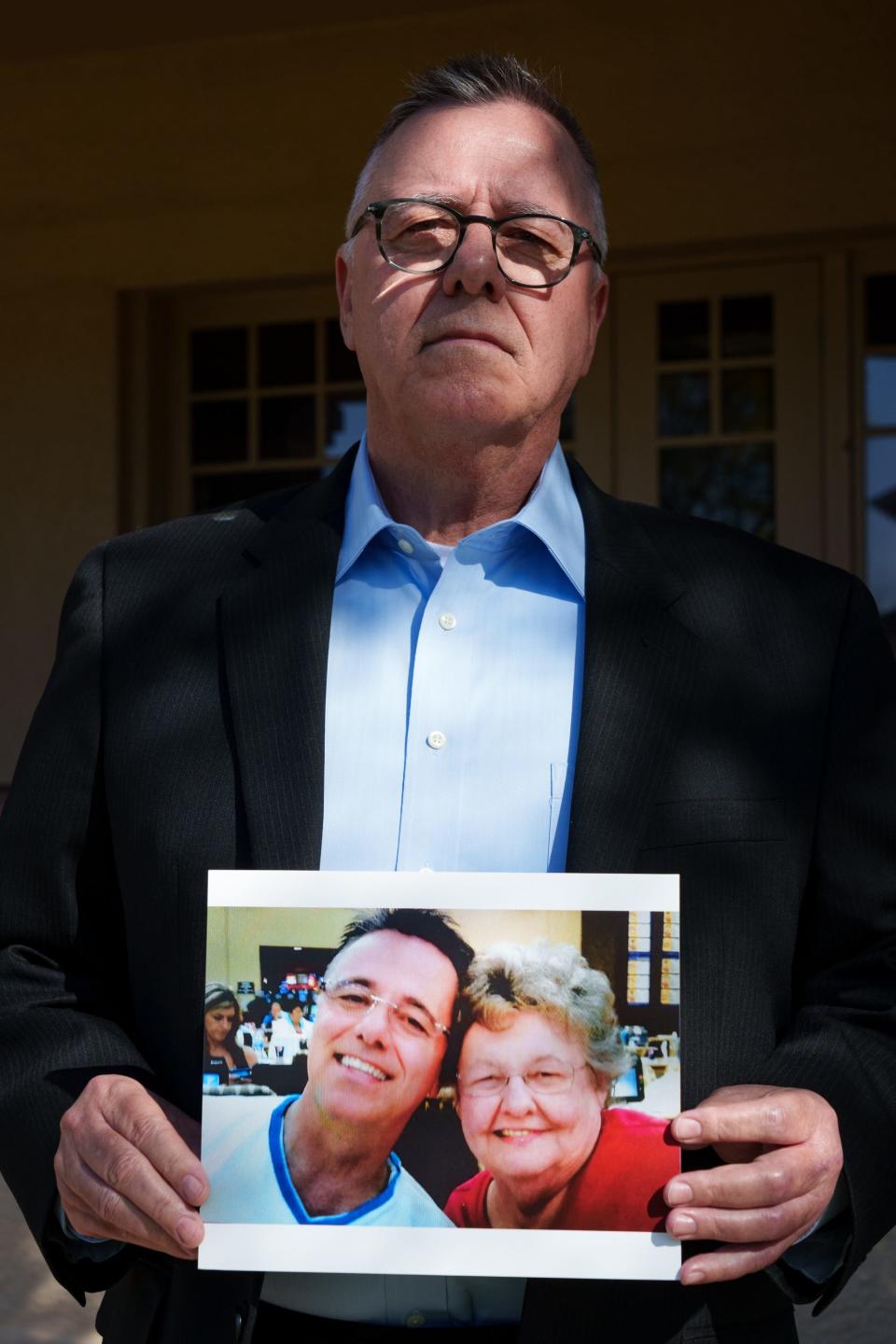 Troy Dinet poses with a photo of him and mother, Joyce Dinet, on March 17, 2023 in Phoenix.