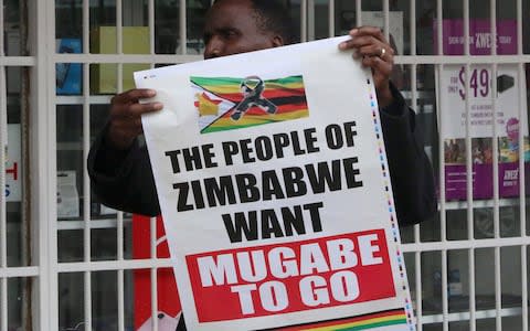 A man carries a poster calling for Zimbabwe President Robert Mugabe to step down  - Credit: PHILIMON BULAWAYO