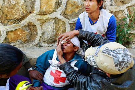 A volunteer with the Myanmar Red Cross Society, is helped after being wounded when the convoy he was in, was fired upon by the Myanmar National Democratic Alliance Army (MNDAA), according to the Myanmar army, between the capital of Kokang, Laukkai, and Chinshwehaw, February 17, 2015. REUTERS/Soe Zeya