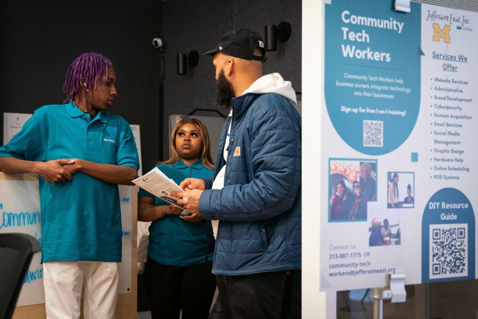 Detroit residents Edwin Taylor, 22, left, and Diamond Hatcher, 21, who works for the Community Tech Worker Program, talk to Andre Sherrell, 33, a residential and commercial builder, during a small business resource fair hosted by Jefferson East Inc. at the Neighborhood Resource Hub in Detroit on March 20, 2023.