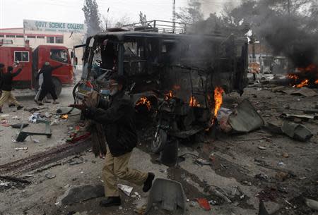 A policeman calls for help as he stands near a burning site after a bomb blast in Quetta March 14, 2014. REUTERS/Naseer Ahmed