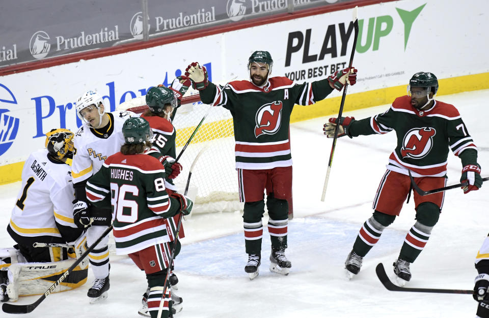 New Jersey Devils right wing Kyle Palmieri (21) celebrates his goal with Sami Vatanen (45), Jack Hughes (86) and P.K. Subban (76) as Pittsburgh Penguins right wing Bryan Rust (17) and goaltender Casey DeSmith (1) react during the first period of an NHL hockey game Saturday, March 20, 2021, in Newark, N.J. (AP Photo/Bill Kostroun)